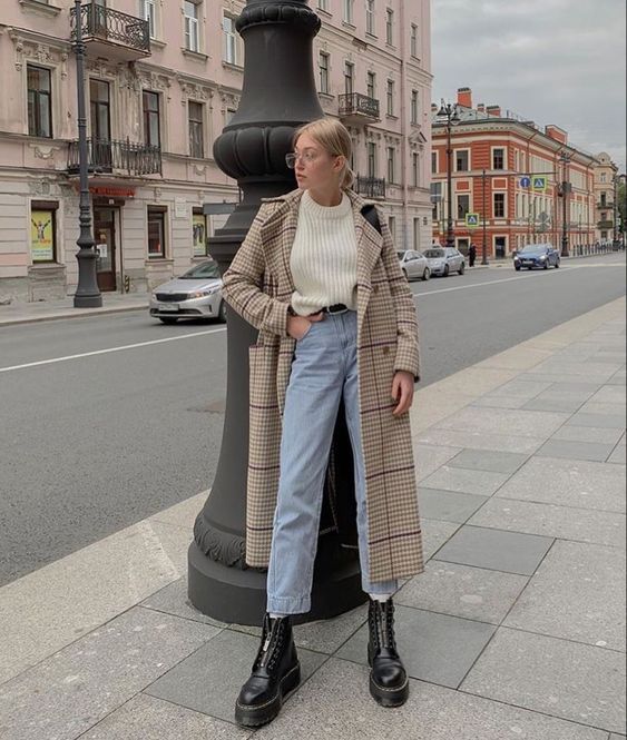 Mulher usando casaco alongado, calça jeans e botas pretas 