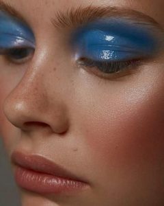 Mulher branca usando maquiagem azul estilo glossy