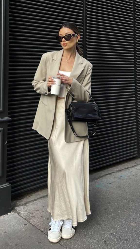 moça jovem e magra usando saia de cetim, blazer e tenis