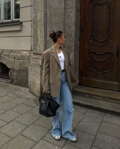 Mulher branca e magra usando blazer oversized, calça jeans e tênis