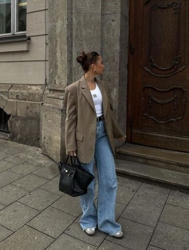 Mulher branca e magra usando blazer oversized, calça jeans e tênis