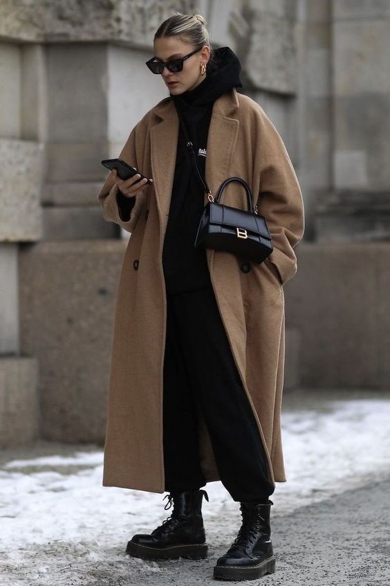 Mulher usando look com moletom preto e casaco