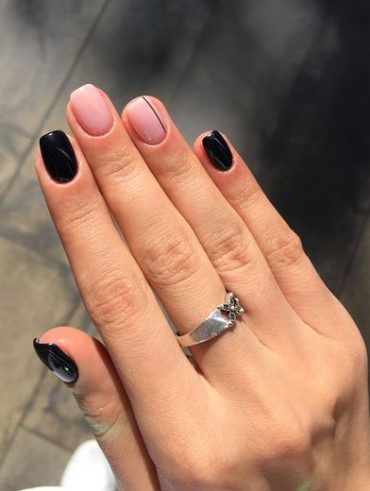 Mão branca com anel prata; Unhas pretas e nude