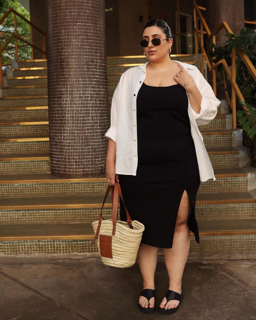 Carla Mortiz usando camisa branca, vestido preto, bolsa de palha e sandália de dedo plataforma