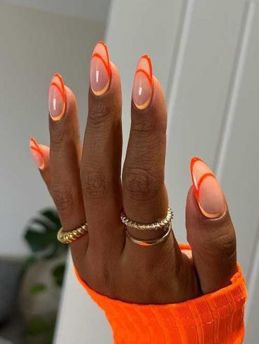 Mão negra com anéis dourados e unha transparente com francesinha normal, dupla e invertida laranja