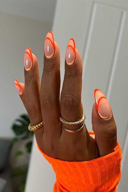 Mão negra com anéis dourados e unha transparente com francesinha normal, dupla e invertida laranja 