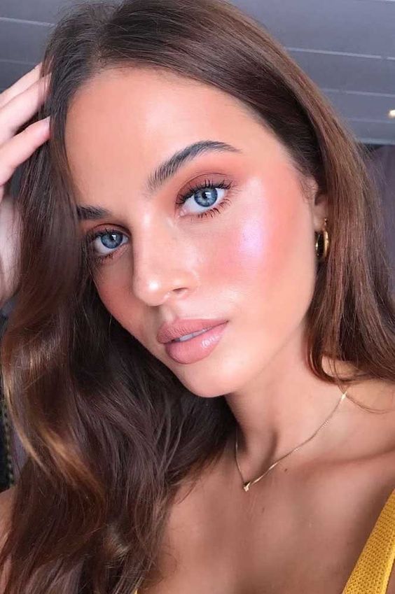 Mulher branca com maquiagem rosada e iluminador rosa 