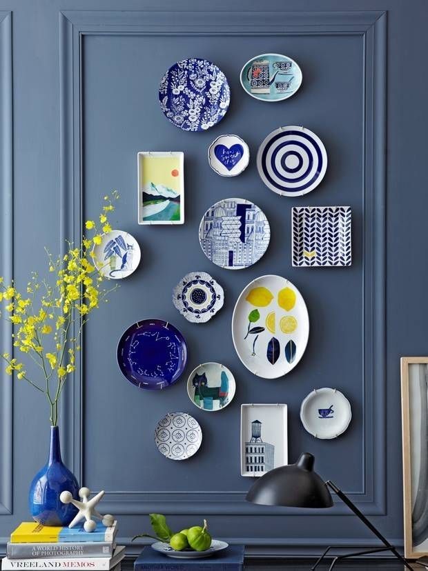 Parede azul com quadros decorativos de tamanhos e formas variados