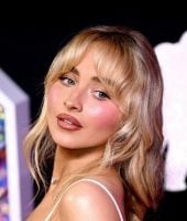 Sabrina Carpenter com cabelo loiro preso e maquiagem rosada e iluminada