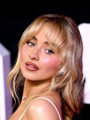 Sabrina Carpenter com cabelo loiro preso e maquiagem rosada e iluminada