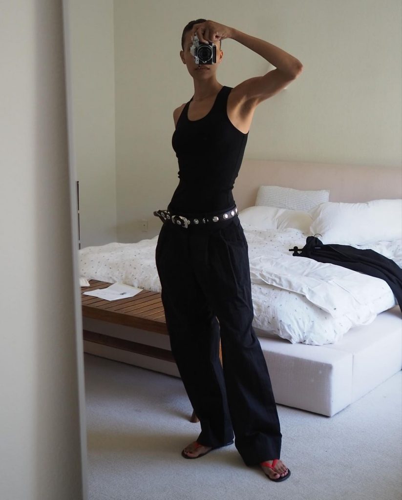 TyLynn Nguyen usando regata preta, calça ampla, cinto fashion e chinelo de dedo
