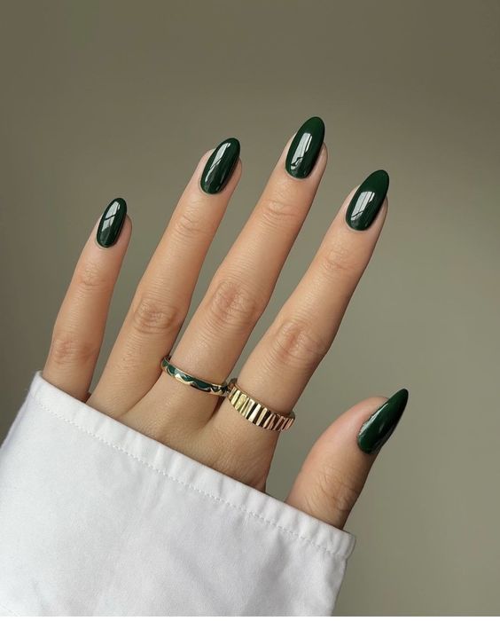 Mão branca com anéis e unha amendoada verde escuro 