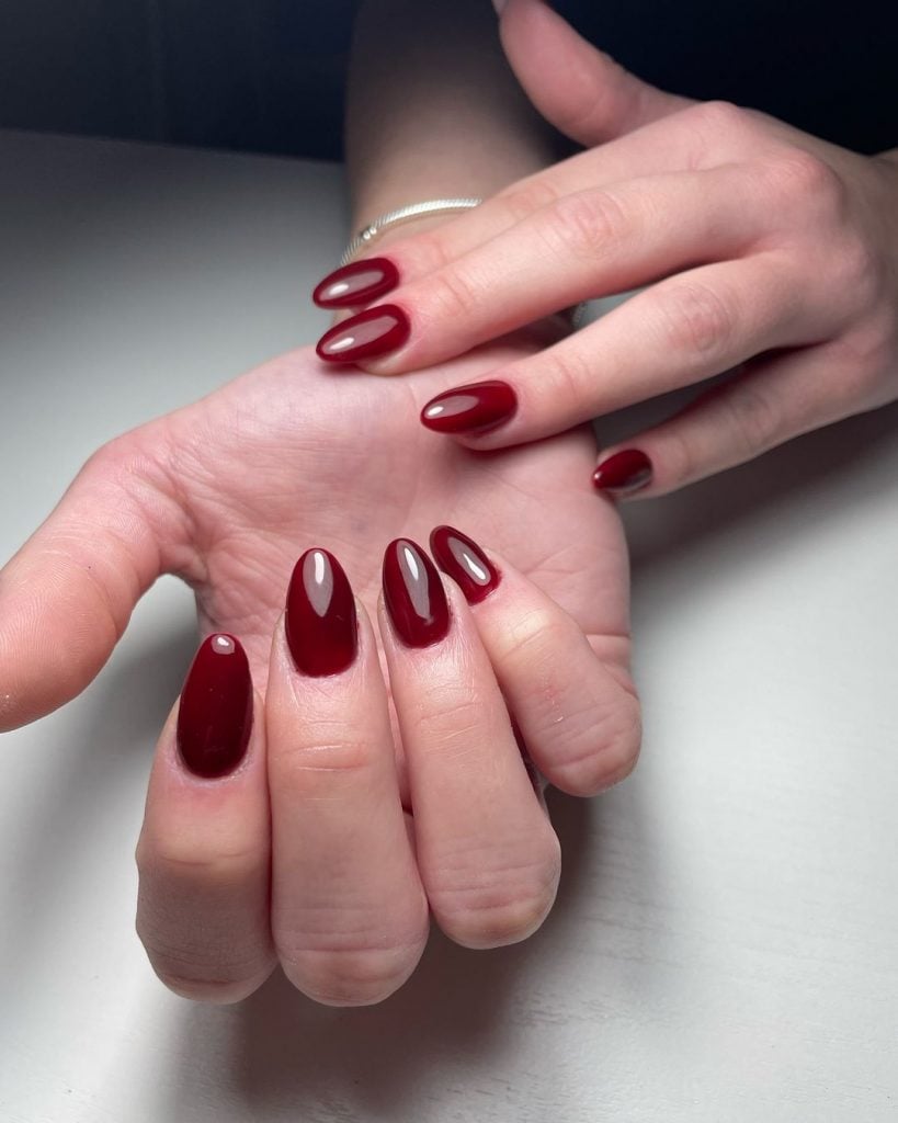 Mãos brancas com unha amendoada vermelho cereja 