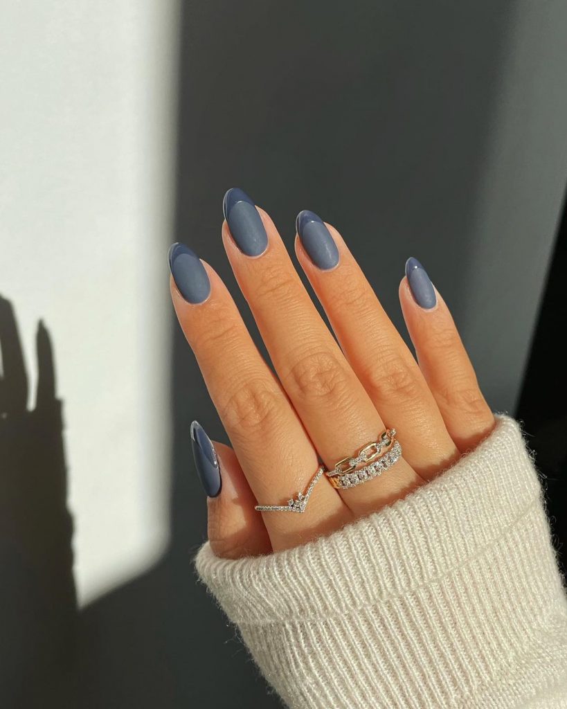 Mão branca com anéis e unha azul acizentado fosca com francesinha brilhante