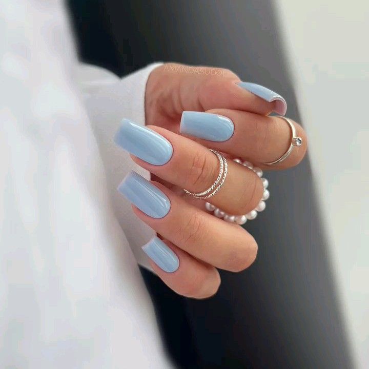 Mão branca curvada com anéis e unha bailarina azul claro 