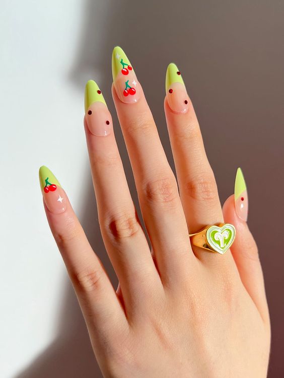 Mão branca com anéis e unha amendoada com francesinha verde, strass e cerejas 