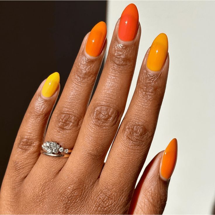 Mão negra com anel prata e unha amendoada laranja degradê