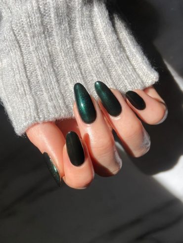 Mão branca curvada com unha amendoada grande verde escuro com glitter