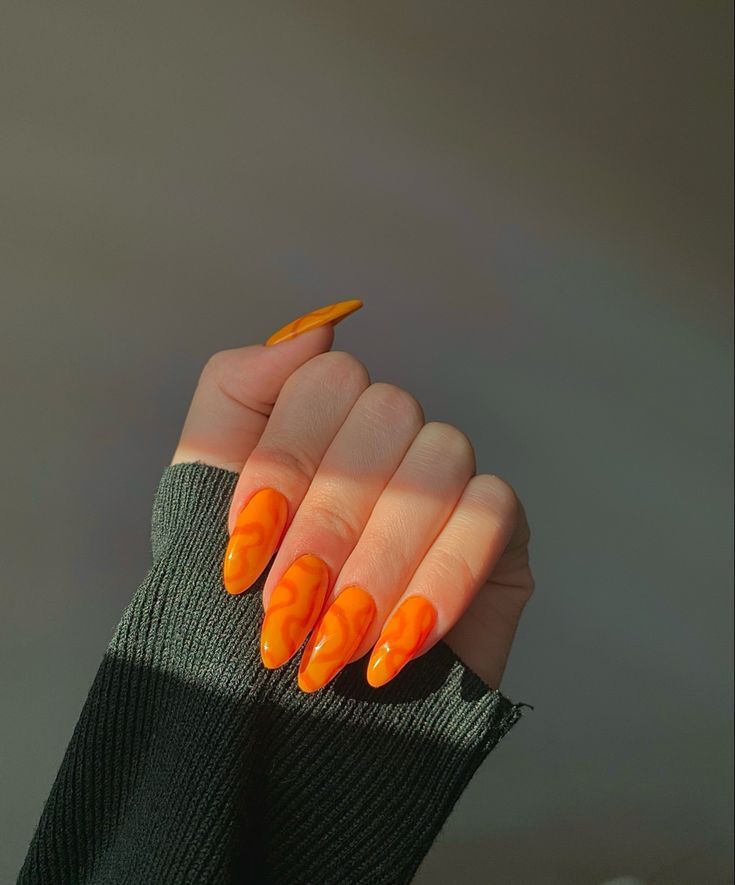 Mão branca curvada com unha laranja decorada com linhas orgânicas