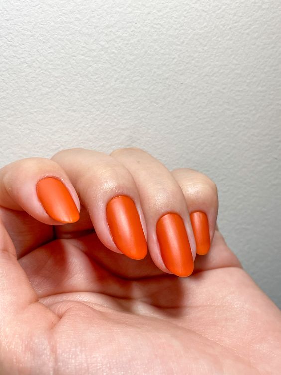 Mão branca curvada com unha laranja queimado fosca 