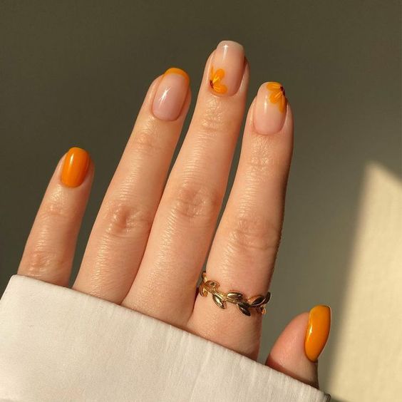 Mão branca com anel e unha quadrada laranja decorada 