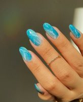 Mão branca com anel e unha azul claro marmorizada