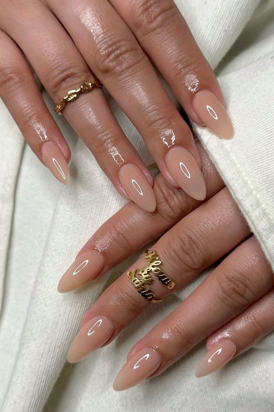Mãos brancas com anéis sobrepostas com unha stiletto nude 