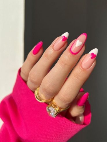 Mão branca com anéis dourados e unha rosa, com francesinha branca e corações