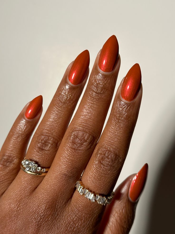 Mão negra com anéis prata e unha stiletto laranja metálica