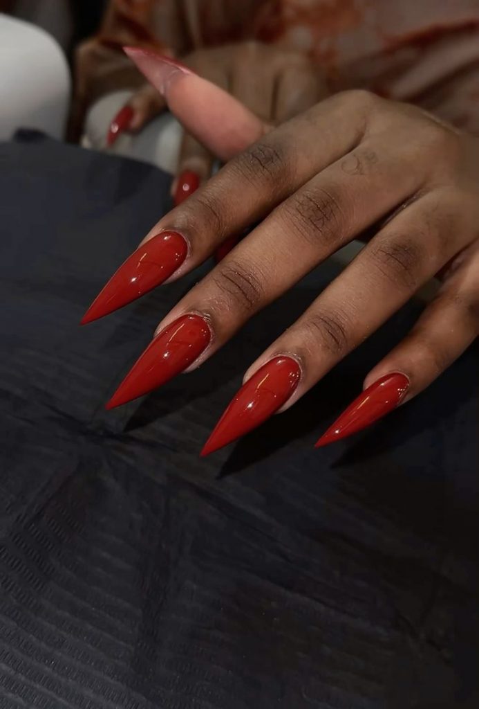 Mão negra aberta com unha stiletto vermelho sangue 