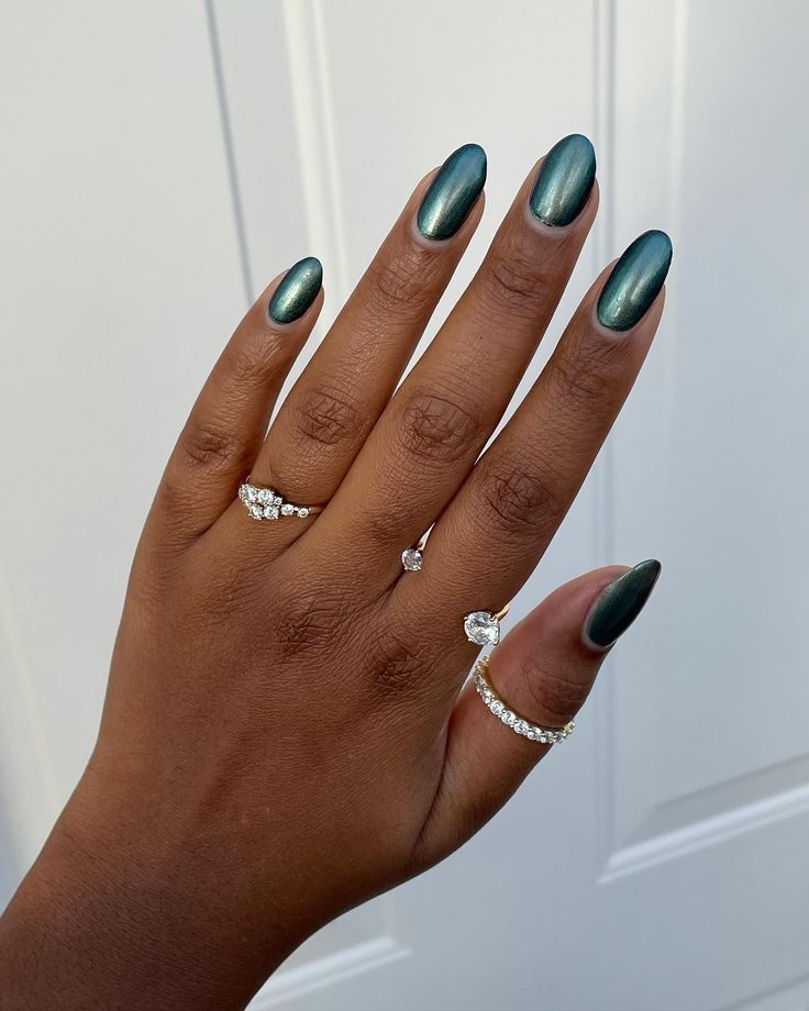Mão negra com anéis pratas e unha verde esmeralda cromada