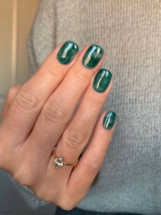 Mão branca com anel e unha quadrada curta verde esmeralda decorada