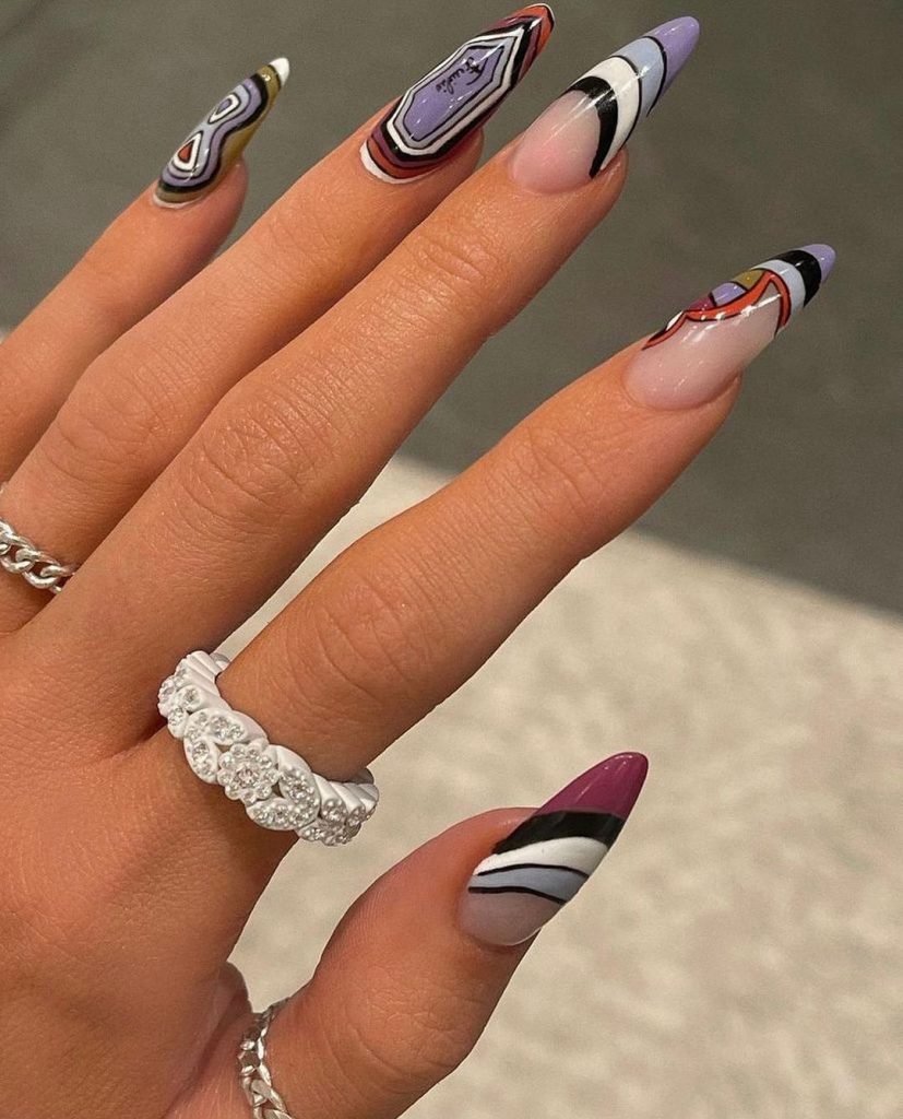 Mão branca com anéis e unha stiletto com formas geométricas