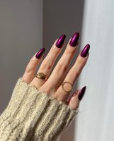 Mão branca com anéis e unha roxa metálica