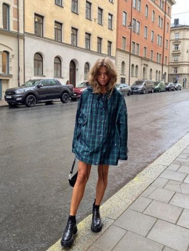 Mulher jovem e loira com camiseta xadrez e bota de cano curto preta