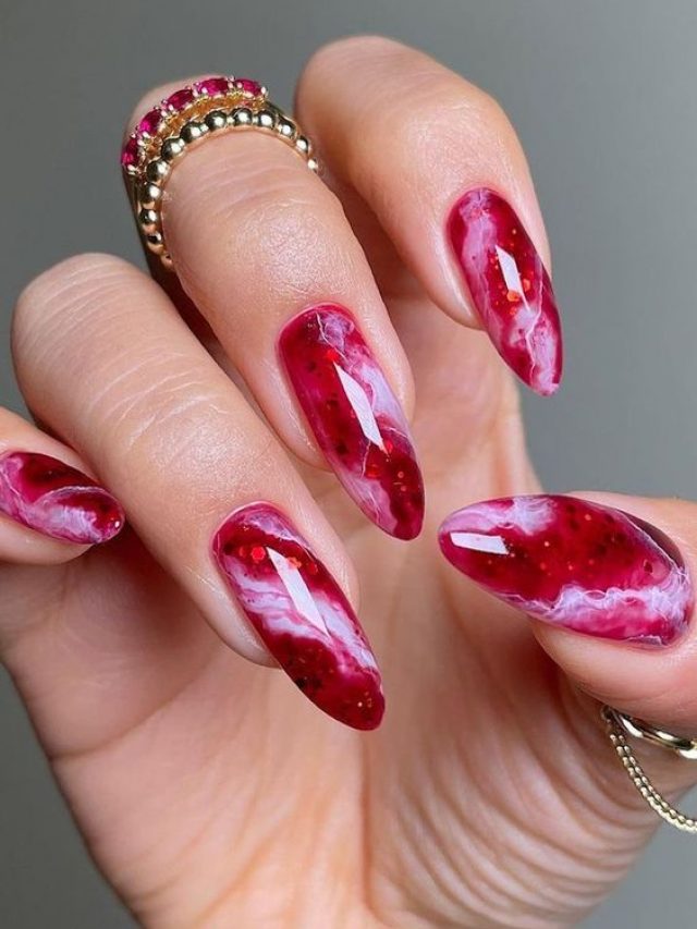 Mão branca curvada com anéis e unha magenta marmorizada