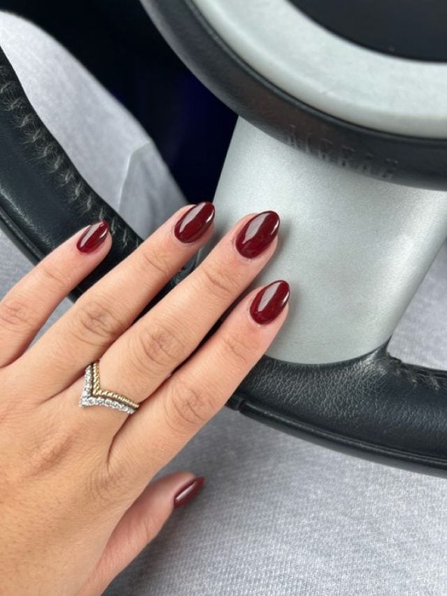 Mão branca com anel prata e unha redonda vermelho cereja