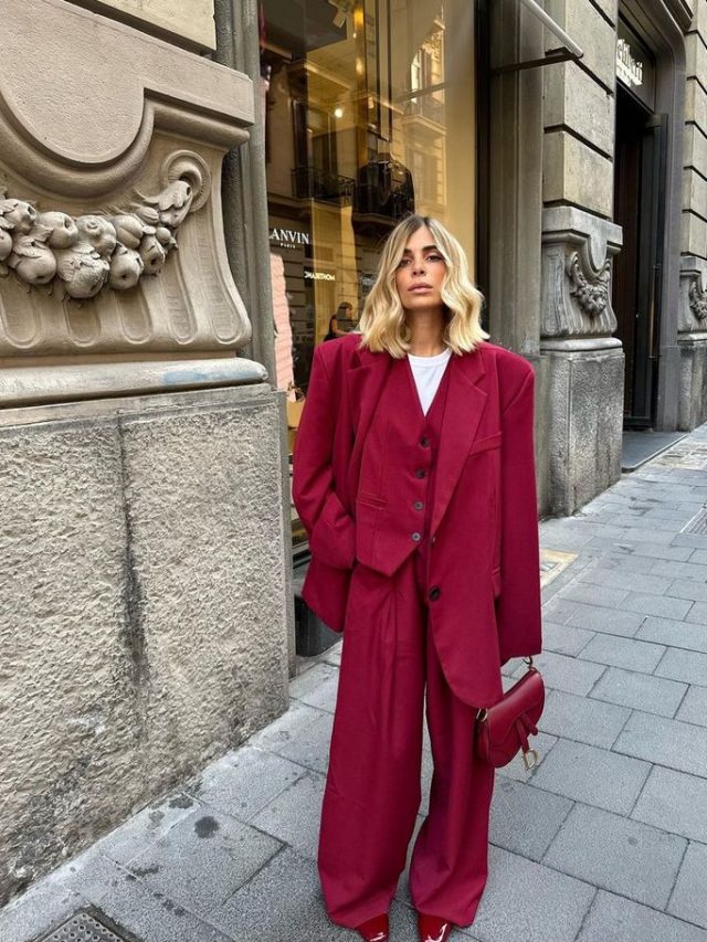 Mulher jovem de cabelo claro. Ela está de blazer e calça vermelha.