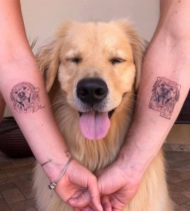 golden retriever de olhos fechados e lingua para fora. Ao lado dele estão dois braços com duas tatuagens de cachorro.