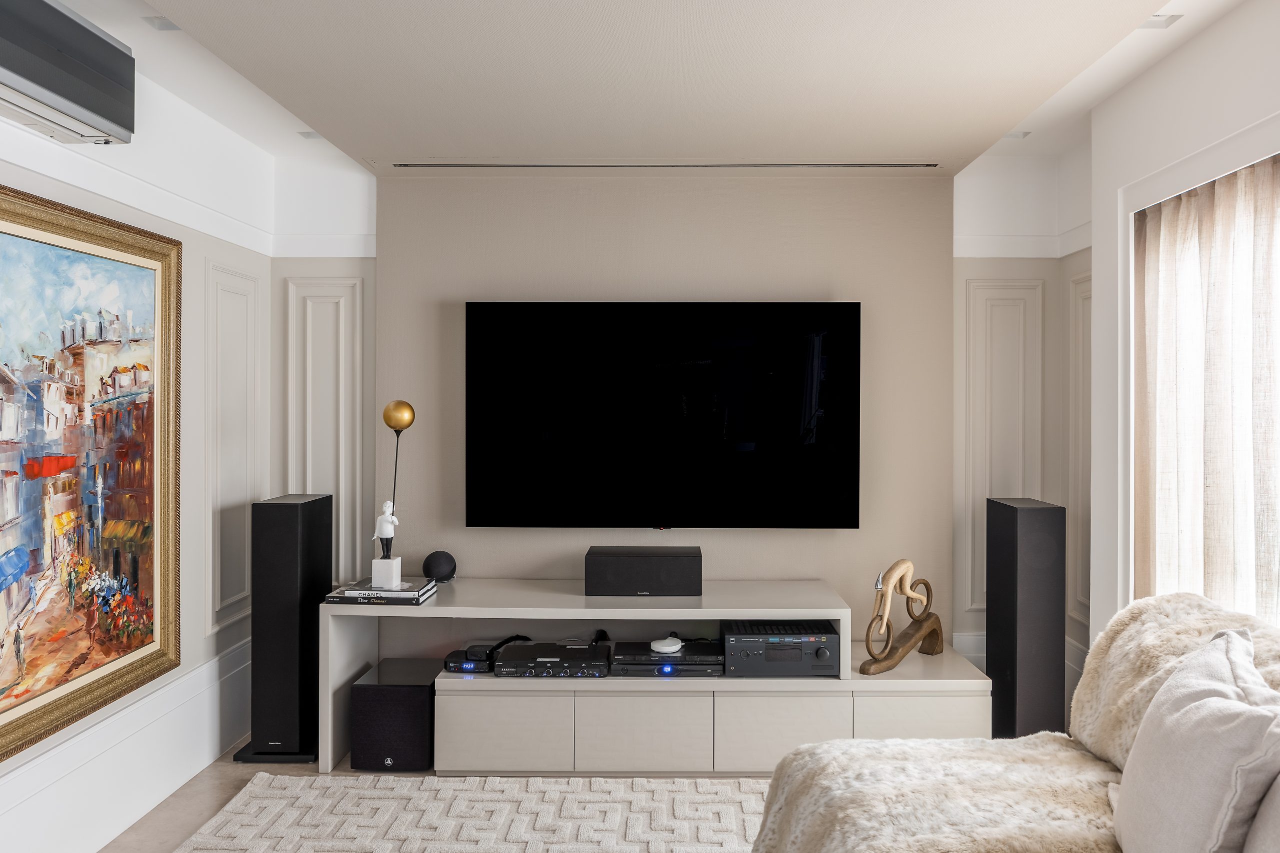 Sala de estar em cor neutra com painel de TV até o teto