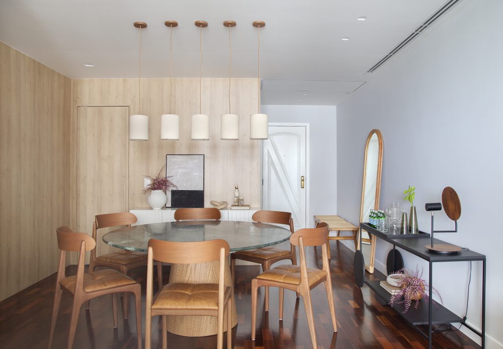 Sala de jantar com mesa de tampo de vidro, cadeiras em madeira e couro