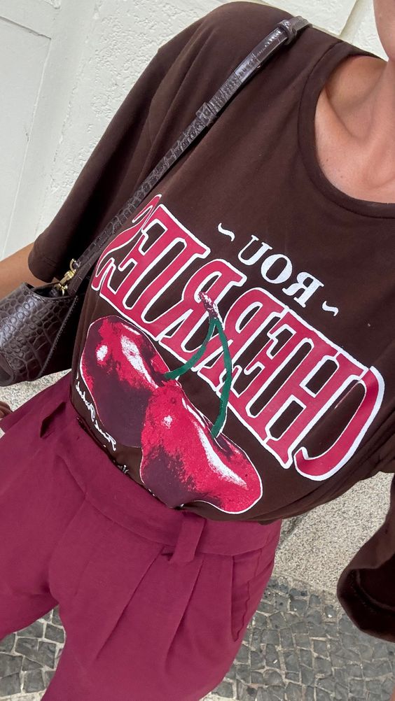 Look com camiseta marrom e estampa de cereja. Com calça de alfaiataria em cor vinho.