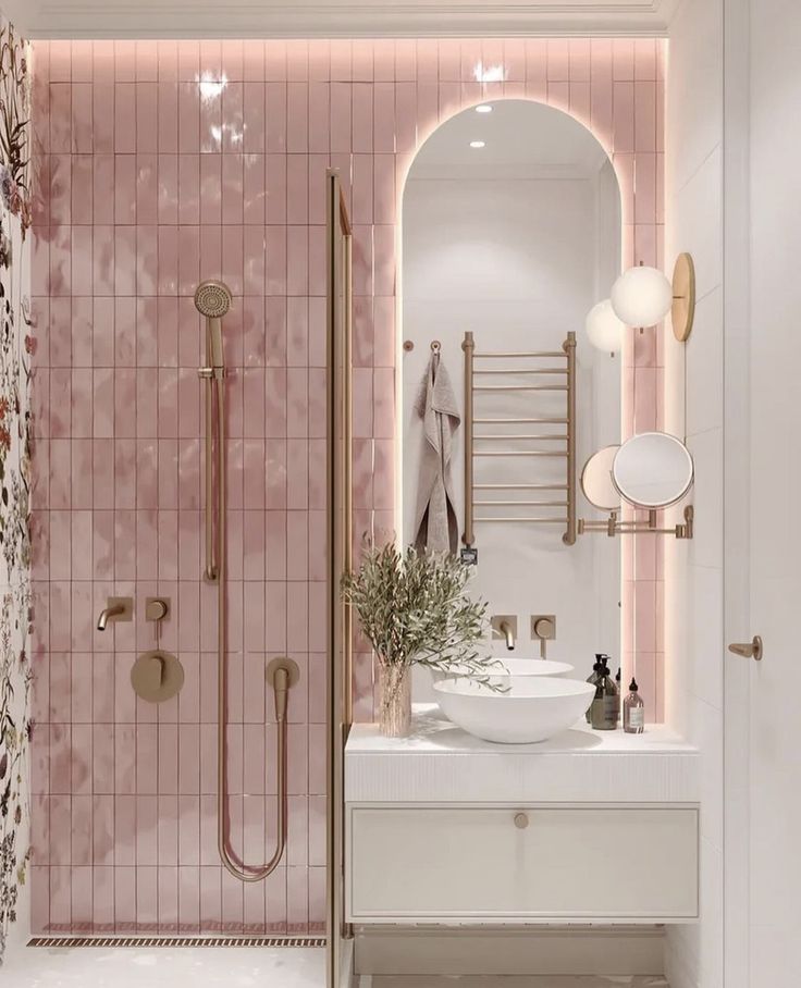 Banheiro com azulejos rosas e louças brancas, com detalhes em rose gold