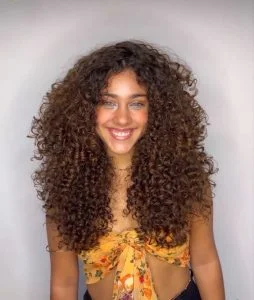 Mulher com cabelo cacheado, repicado e longo