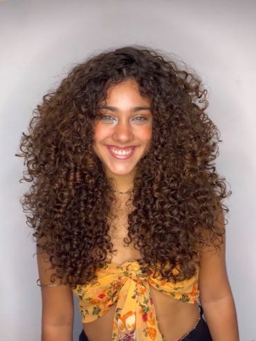 Mulher com cabelo cacheado, repicado e longo