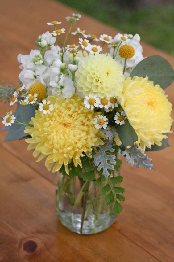 Vaso de vidro com flores do campo brancas e amarelas