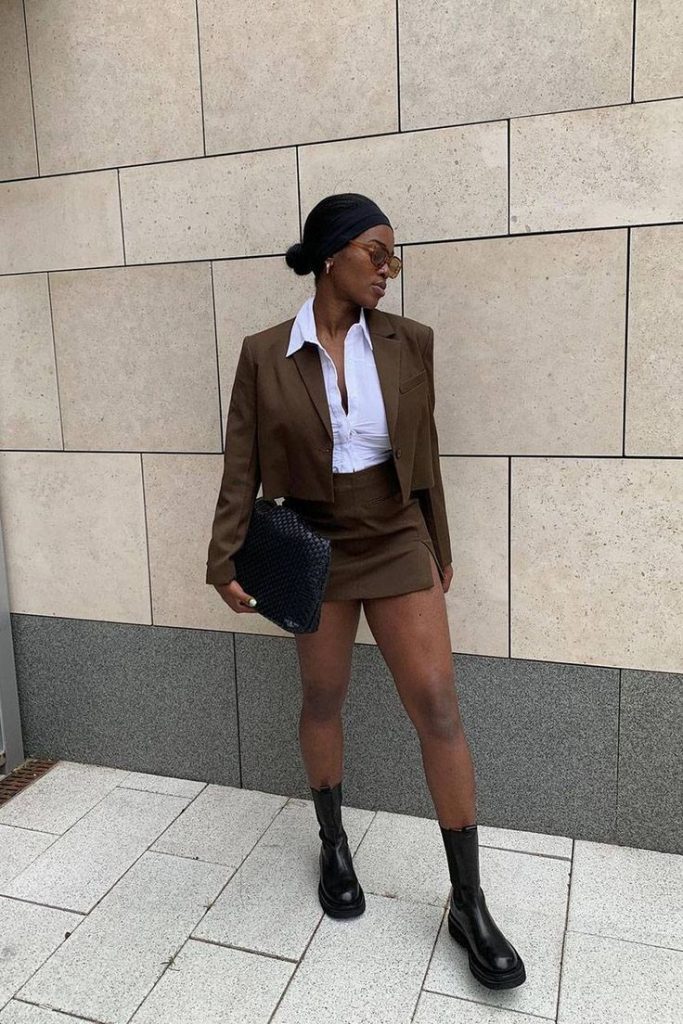 Georgia usando faixa de tecido no cabelo, camisa branca e conjunto de alfaiataria de blazer e minissaia com bota Chelsea de cano curto
