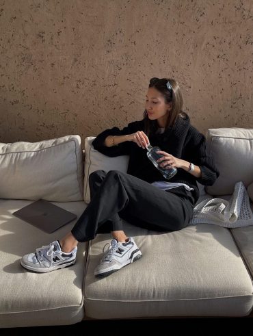 Felicia Akerstrom usando calça de alfaiataria preta, blusa de tricô e tênis New Balance