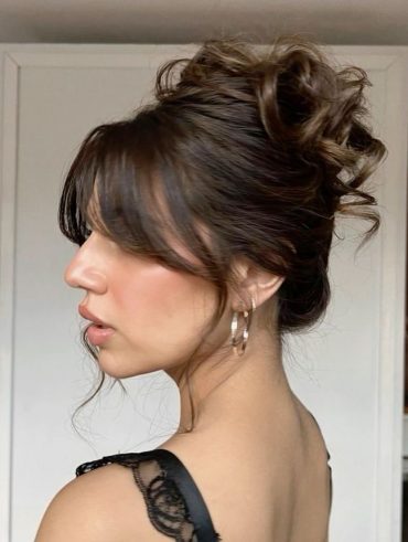 Mulher branca com cabelo liso, preso e com franja Bardot