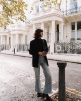 Chloe Miles com corte de cabelo french bob, usando jeans e blazer preto